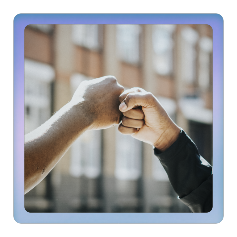 Zwei Hände treffen sich zum Fistbump vor einem unscharfen Hintergrund.