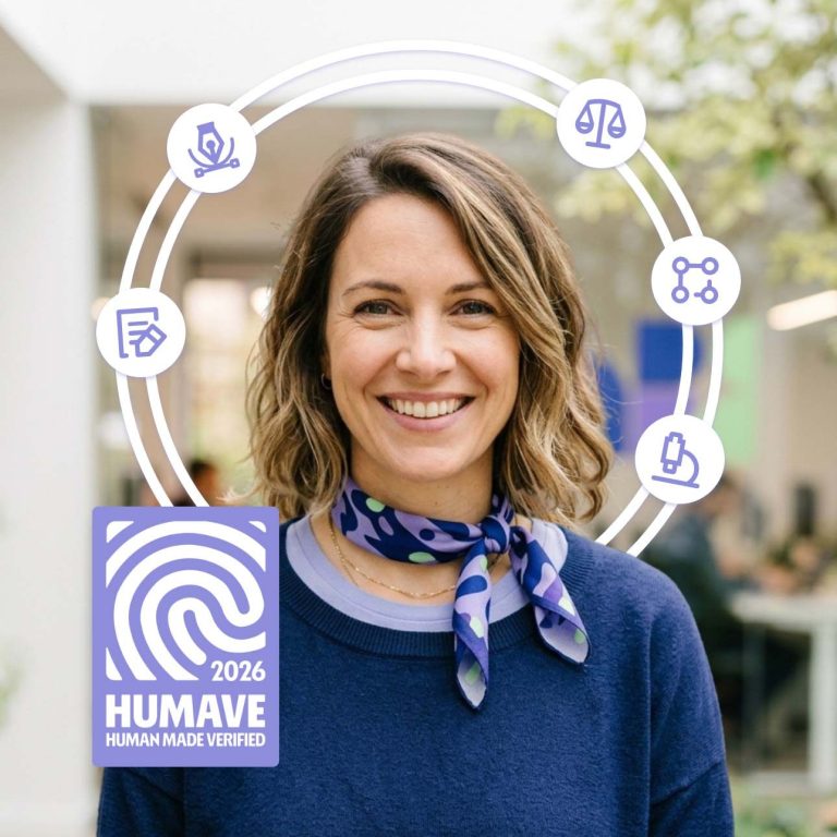 Frau mit schulterlangem Haar, blauem Pullover und Schal, lächelt vor einem modernen Hintergrund.